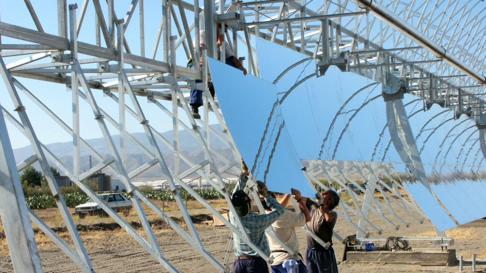 Workers install a reflective parabolic trough at a solar thermal power plant in Spain.